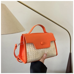 Détail d'un sac bandoulière en paille avec finitions en cuir orange et bouton pression