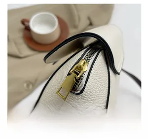 Detail of premium gold metal zipper on off-white pebbled leather crossbody shell bag