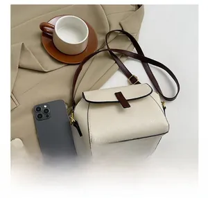 Detail of off-white crossbody bag with pebble leather texture and size comparison