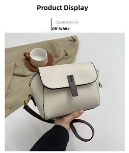 Detail of beige litchi grain leather square bag with contrast trim and gold hardware