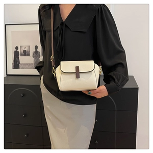 Creamy crossbody bag in pebble grain leather with dark brown strap and buckle detail