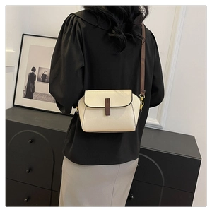 Detail showing the creamy white lychee pattern leather texture and chic dark brown shoulder strap