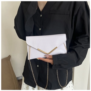Détail pochette enveloppe blanche à texture ondulée, bordure dorée et bandoulière