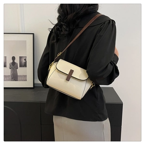 Chic cream leather crossbody bag with brown trim shown styled on a model in a modern room