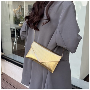 Gros plan détaillé d'un sac enveloppe doré avec texture plissée métallique pour femmes