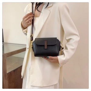 Crossbody black leather shell bag with gold hardware shown on a white blazer outfit