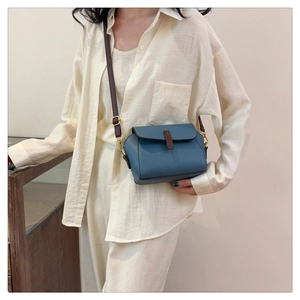 Blue lychee pattern leather crossbody bag shown on model with brown strap detail