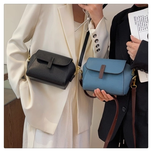 Close-up of small minimalist crossbody bags in black and blue pebbled leather texture