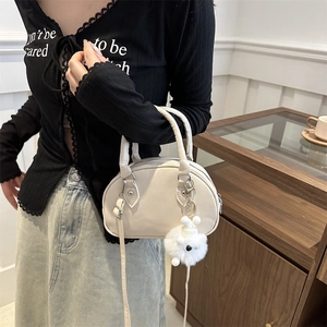 Minimalistische cremeweiße halbmondförmige Handtasche mit Riemen und Plüschanhänger