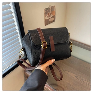 Close-up of black lychee-textured faux leather crossbody bag with brown strap