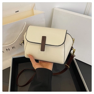 Detail of cream pebbled leather mini crossbody bag with brown straps and gold hardware