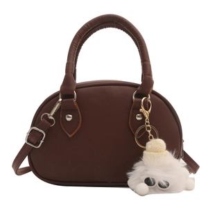 Minimalistische dunkelbraune halbrunde Ledertasche mit Plüsch-Anhänger auf weißem Grund
