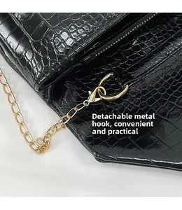 Detail of gold hardware hook and croc-embossed leather on detachable black clutch bag