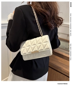 Détail du sac matelassé crème avec boucle dorée et bandoulière chaîne sur un modèle