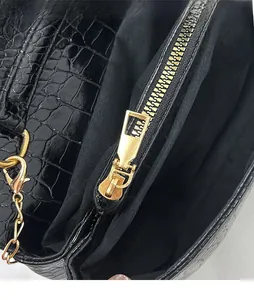Detail of golden zipper slider on black crocodile pattern leather handbag for women