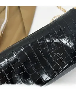Close-up of black crocodile pattern faux leather texture with elegant gold chain strap