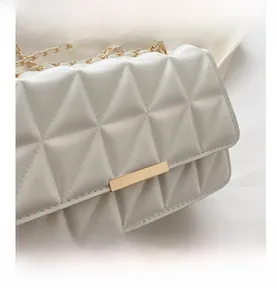 Détail du sac matelassé blanc avec fermoir géométrique doré et bandoulière chaîne