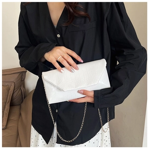 Close-up of white crocodile pattern envelope clutch bag with gold chain shoulder strap
