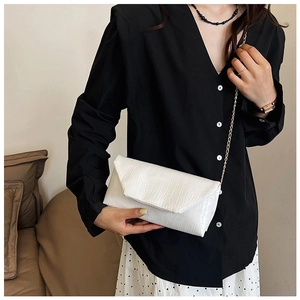 Close-up of a white envelope crossbody bag with crocodile texture and gold chain strap