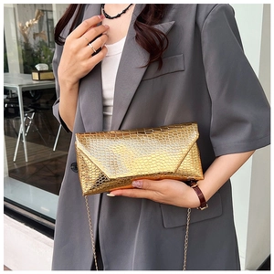 Detail of gold crocodile embossed envelope clutch bag with elegant metal chain strap