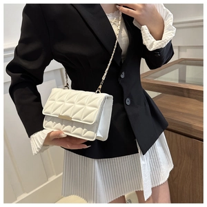 Sac à bandoulière matelassé blanc avec chaîne dorée porté par un mannequin