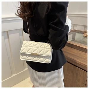 Détail d'un sac bandoulière blanc matelassé avec chaîne dorée sur un mannequin