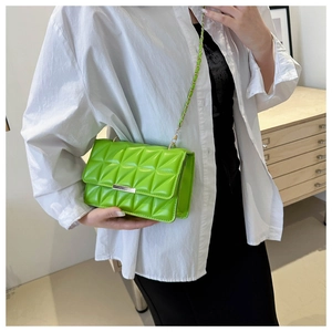 Sac bandoulière vert matelassé avec barre métallique dorée et chaîne porté par mannequin