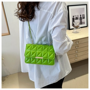 Détail du sac bandoulière matelassé vert vif avec chaîne dorée sur chemise blanche