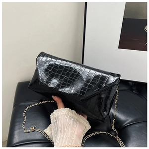 Close-up of black crocodile texture envelope clutch with elegant gold chain strap
