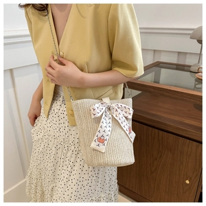 Detail of woven straw bucket bag featuring a printed silk scarf and silver chain strap