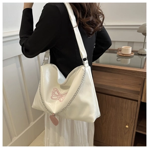 Détail du sac à bandoulière en similicuir blanc avec broderie papillon rose et breloque cœur