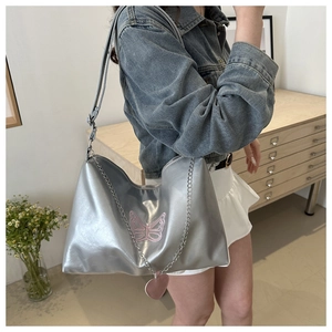 Détail du sac argenté métallisé avec broderie papillon rose et pendentifs cœurs