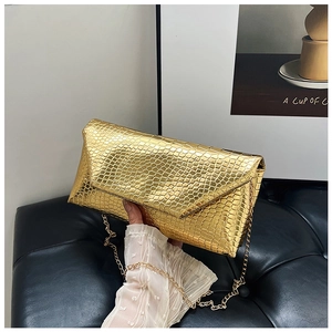 Detailed macro view of the gold chain and crocodile texture on this envelope crossbody bag