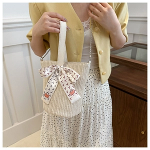 Detail of woven straw bucket bag with decorative silk scarf and metallic chain strap