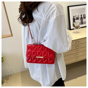 Sac bandoulière rouge matelassé avec boucle dorée et chaîne porté par un mannequin de dos