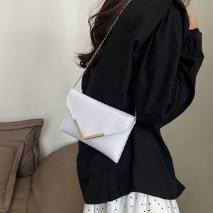 Sac enveloppe blanc avec texture ondulée et bordure métallique dorée en forme de V