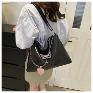 Detail of black PU hobo bag with pink butterfly embroidery and silver heart chain
