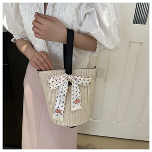 Close-up of woven straw tote bag with V-shaped texture and decorative printed silk scarf