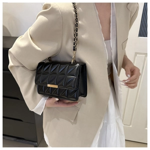Vue détaillée du sac bandoulière noir matelassé avec chaîne dorée porté par un mannequin