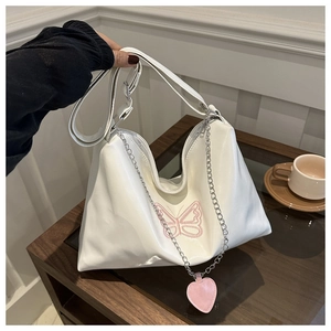 Détail d'un sac en simili cuir blanc avec broderie papillon rose et pendentif cœur
