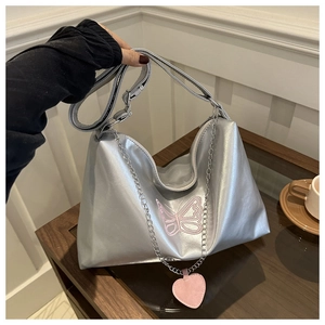Détail du sac cabas argenté avec broderie papillon rose et pendentif en forme de cœur