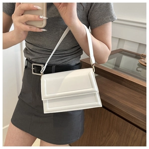 Detailansicht einer weißen rechteckigen Ledertasche mit geprägter Textur am Rand