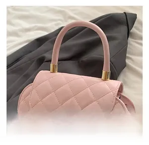 Detailed close-up of pink quilted baguette bag with a round handle and gold hardware