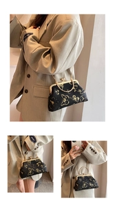 Detail of black fabric handbag with golden butterfly embroidery and metal ring handle