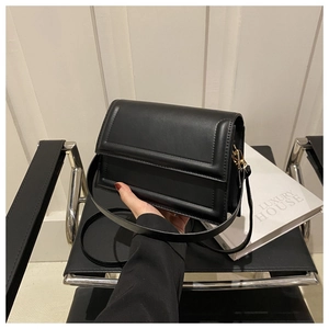 Nahaufnahme der minimalistischen schwarzen Ledertasche mit goldenen Details auf dem Stuhl