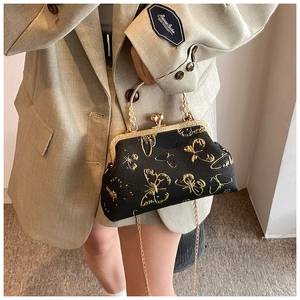 Detail of elegant gold butterfly embroidery on a black silk handbag with metal handle
