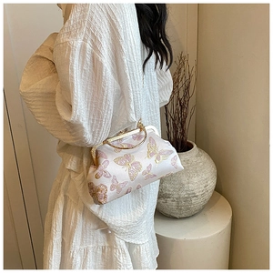 Detail of satin kiss-lock bag with butterfly patterns and round gold metal handle