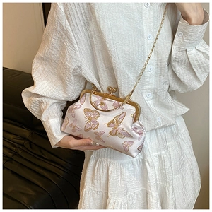 Detail of pink satin clutch bag featuring gold butterfly embroidery and vintage clasp