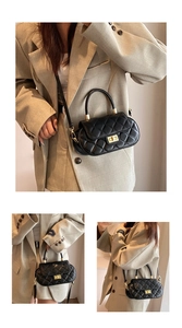 Close-up of black quilted leather baguette bag with golden swivel lock and crossbody strap