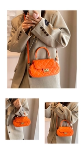 Close-up of orange quilted baguette bag with gold twist lock and elegant top handle